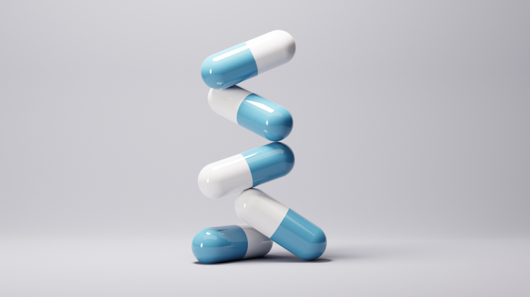 capsules with blue and white halves stacked in a zigzag pattern against a grey background